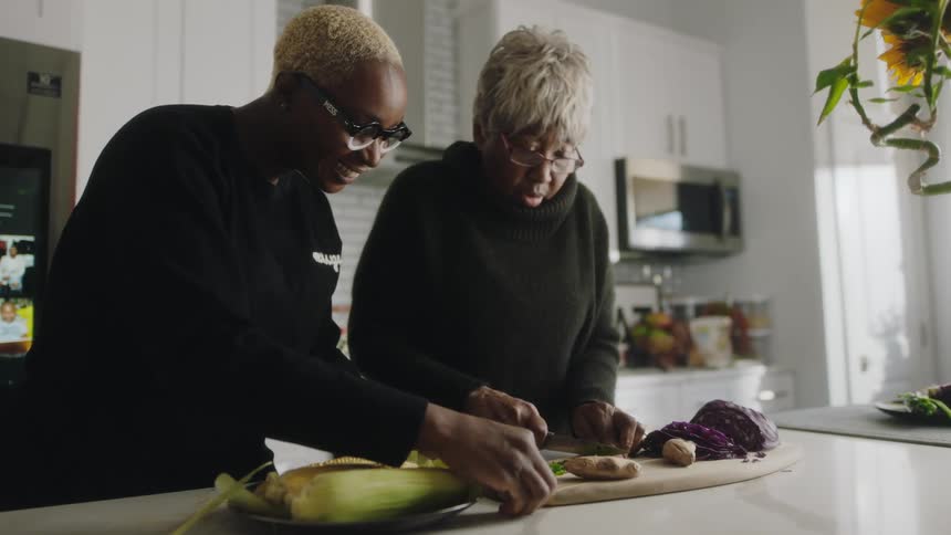 Mother and daughter cooking vegetables together on the kitchen at home