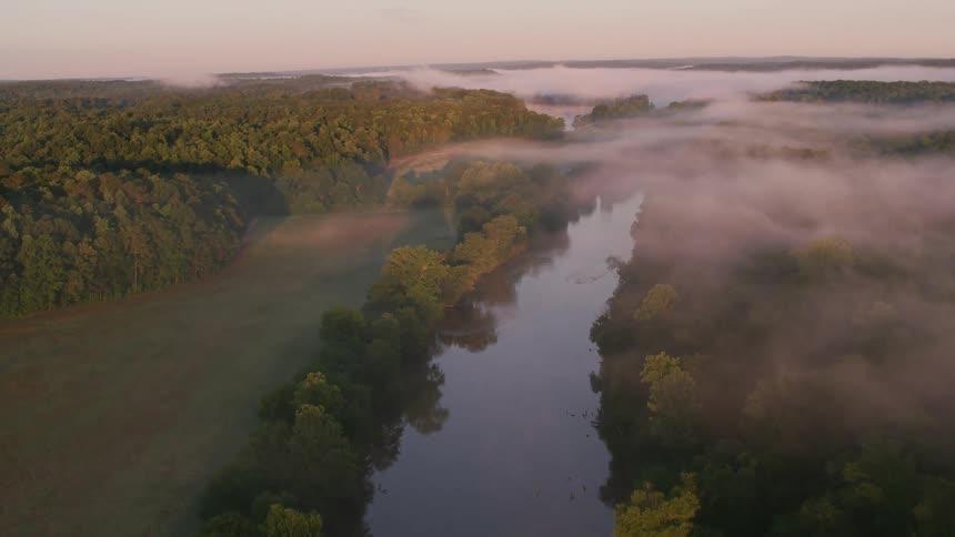 A calm river through a misty countryside in the evening