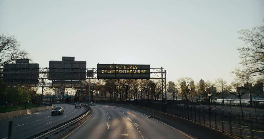 The sun shines brightly on a highway as traffic moves in and out of downtown