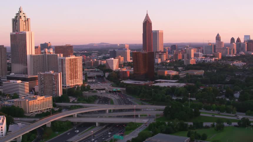 Traffic moves on the big city highway as the sun shines on tall buildings and skyscrapers