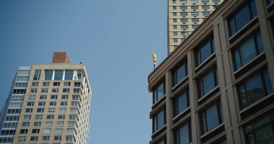 An angel moroni statue on the steeple of a building in a city