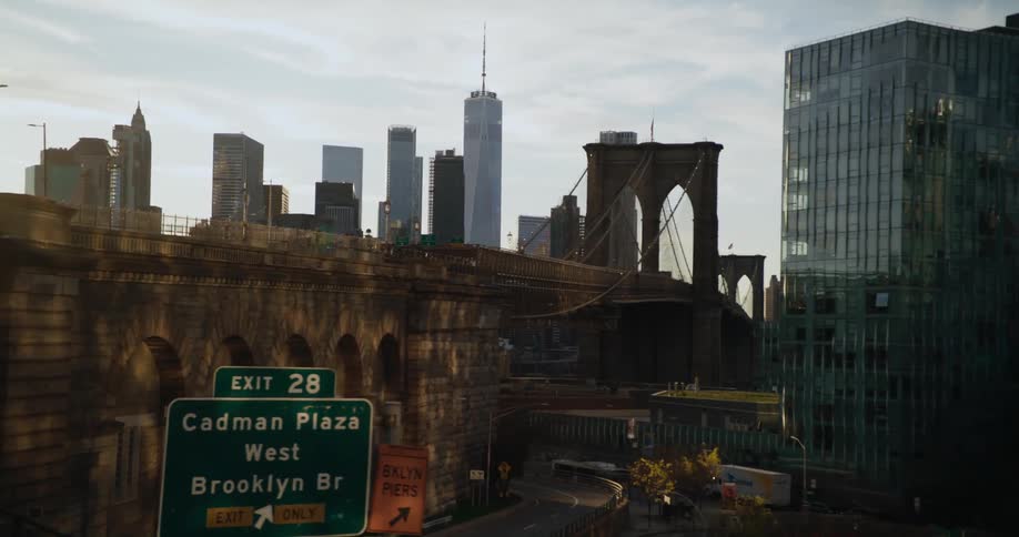 Downtown skyscrapers are visible from the other side of a bridge along a highway exit