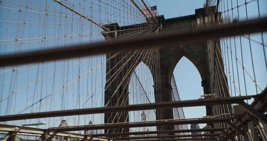 Vehicle crosses suspension bridge with tower and american flag