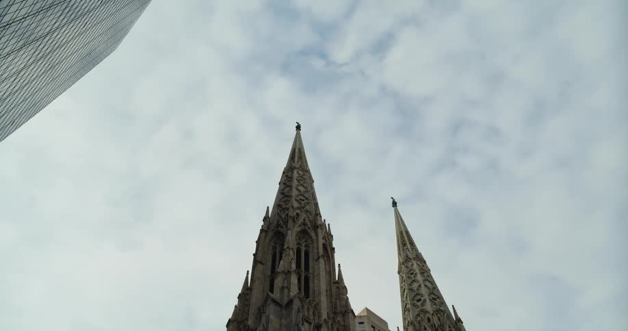 A gothic style building with pointed steeples sits below a tall skyscraper