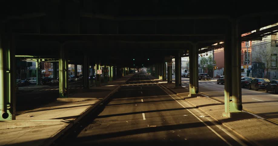 Subway tracks sit on columns over a road running through a city neighborhood