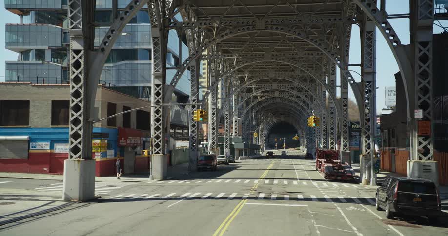 A street running under a large bridge in a metropolis during the day