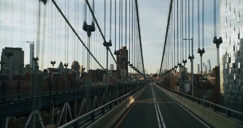 Traveling over a suspension bridge surrounded by buildings in a big city