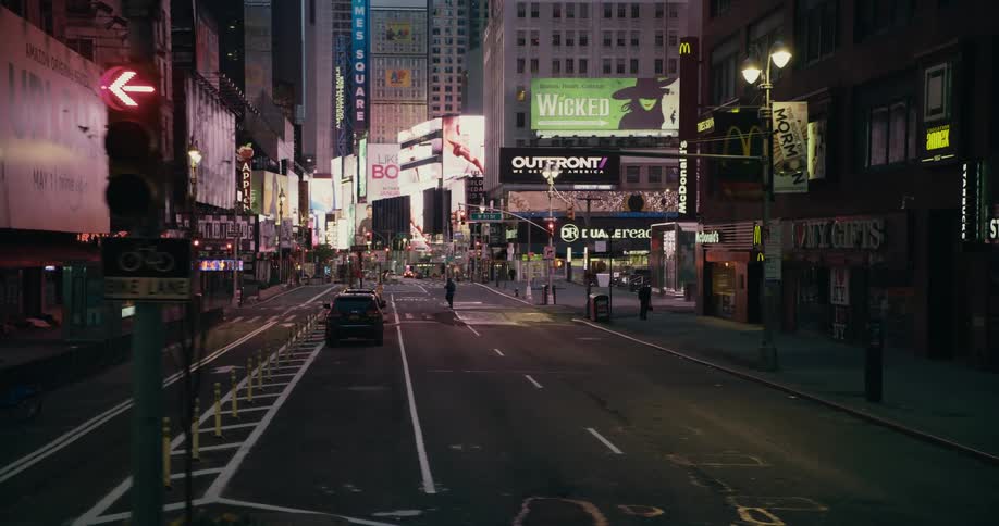 People cross the street in a city neighborhood filled with colorful billboards