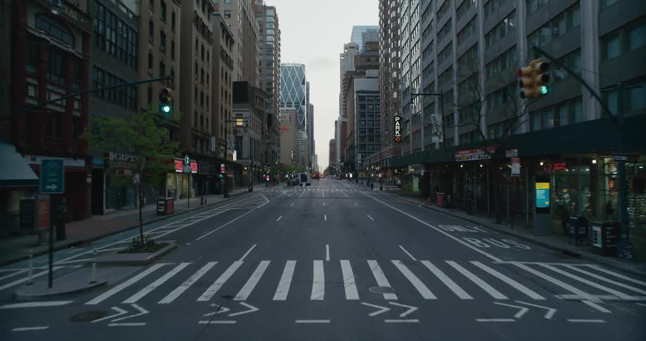 Vehicle drives through city street with high rise buildings