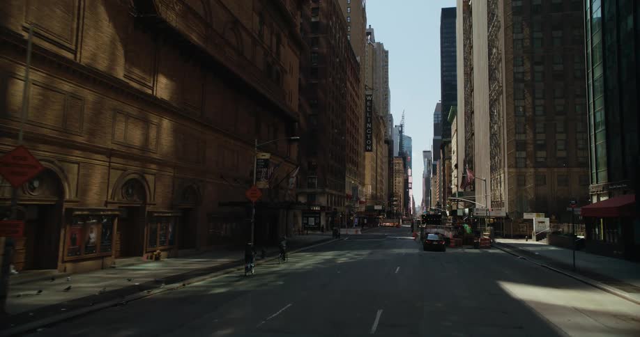 People are on a downtown street walking and riding bikes past tall buildings