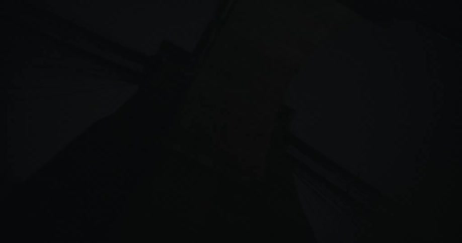 American flag flutters on flagpole sitting on suspension bridge at night