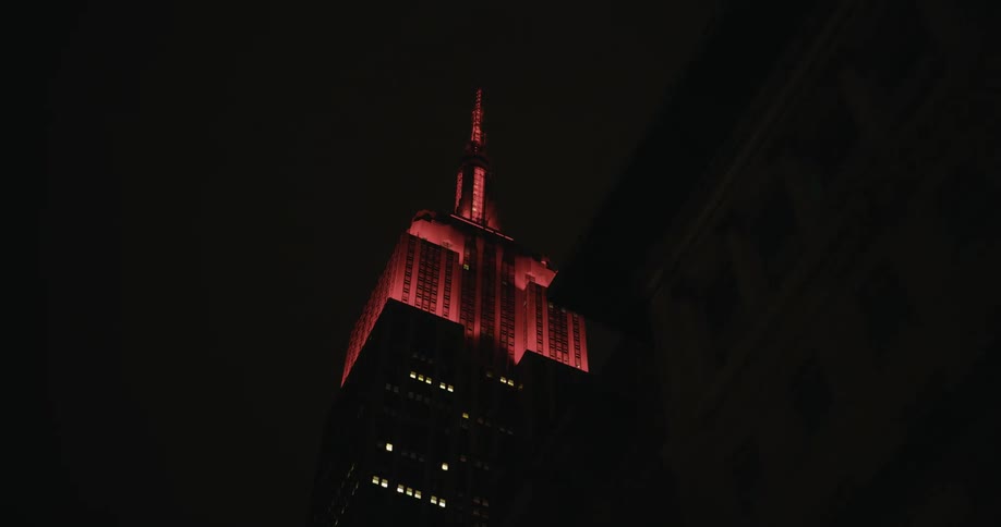 The top of a tall skyscraper glows and flashes red