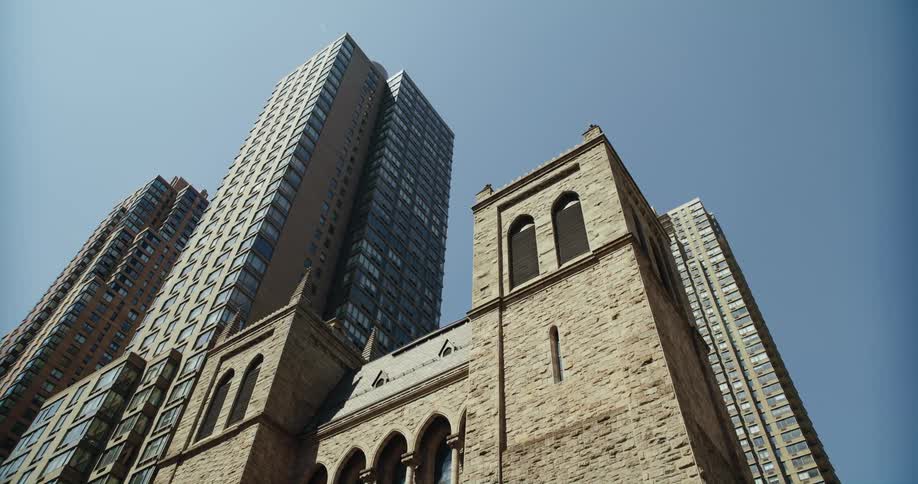 Saint pauls church in manhattan surrounded by high rise buildings under a bright blue sky