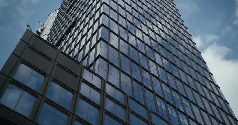 The reflections of nearby buildings shine on the surface of a tall downtown building