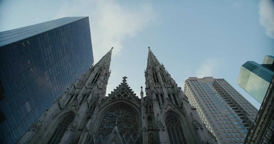A cathedral with elaborate architecture is located between two tall skyscrapers