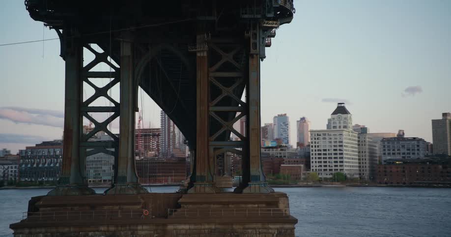 Traveling under the manhattan bridge in new york city at sunset