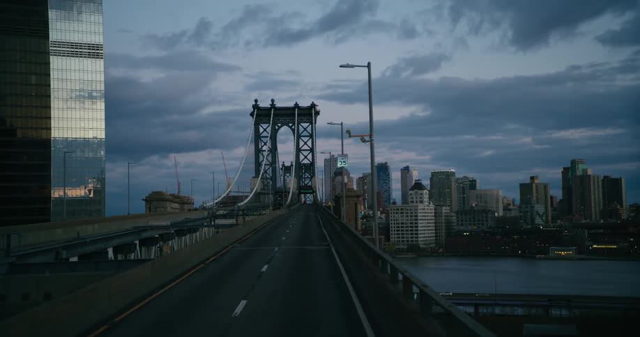Mirrored surface of skyscrapers standing near river spanning suspension bridge reflects red horizon