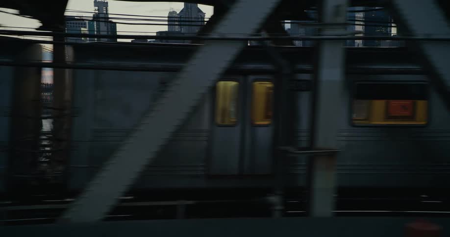 Traveling past a train on a bridge in front of buildings and skyscrapers in a city