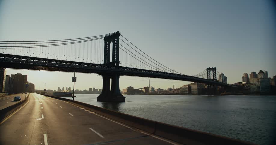 Vehicles drive on a highway that goes under a bridge leading to downtown