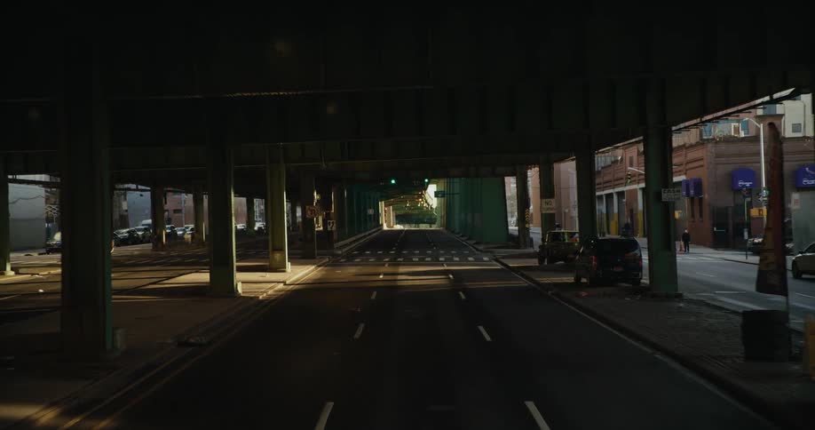 Traveling on an empty city street under an elevated train platform