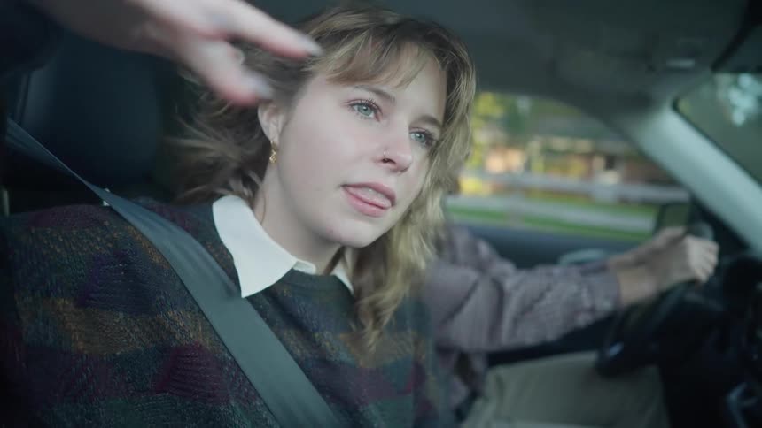 A woman riding in the car waves her hand out the window