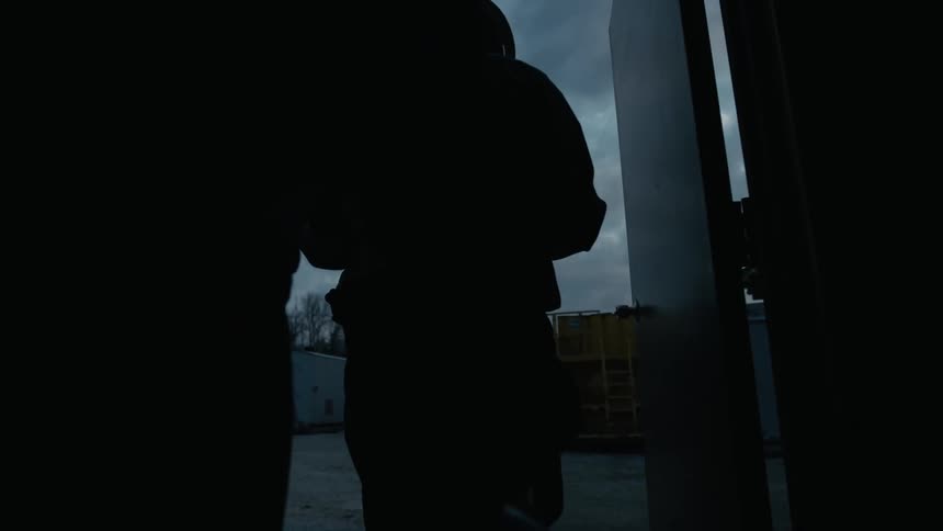 The silhouette of three men leaving through a doorway each one putting on a hardhat