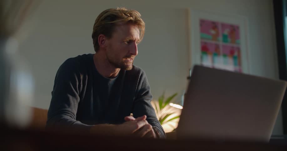 Man sits and holds conversation via laptop