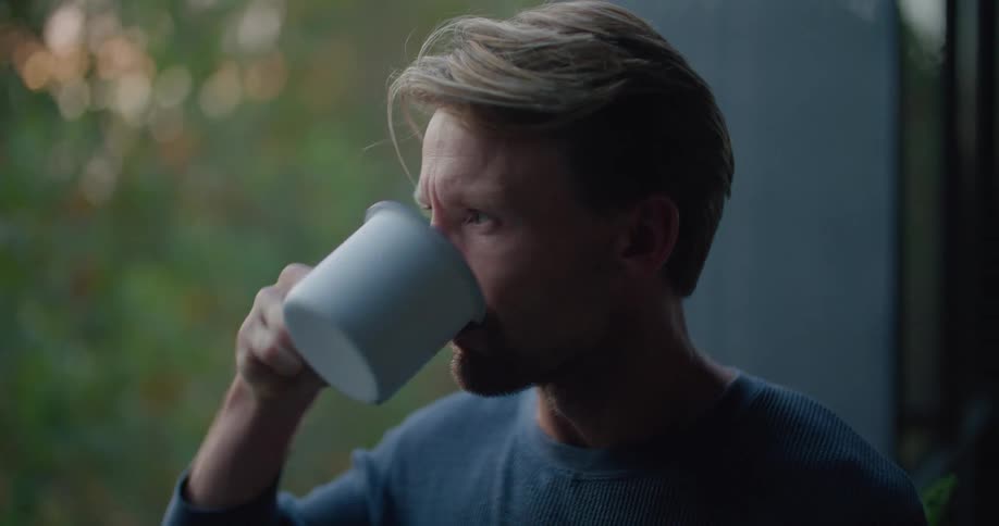 Man stands on porch drinking coffee before walking back