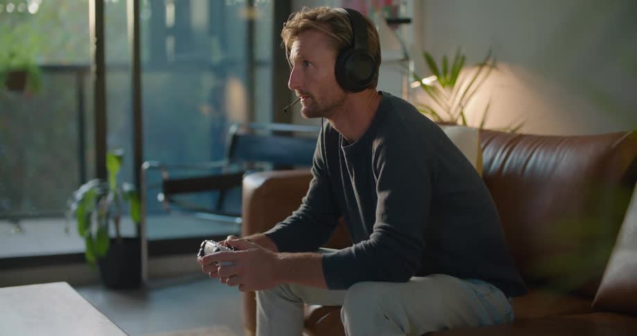 A man wears headphones while playing video games at home