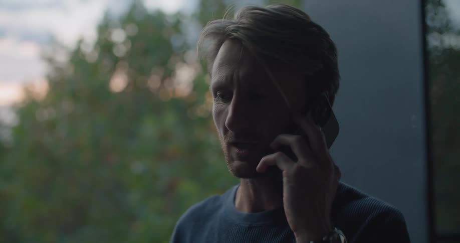 A man is talking on a phone and drinking coffee