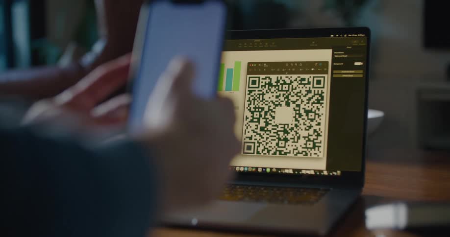 A man uses his smartphone to scan a qr code on his laptop