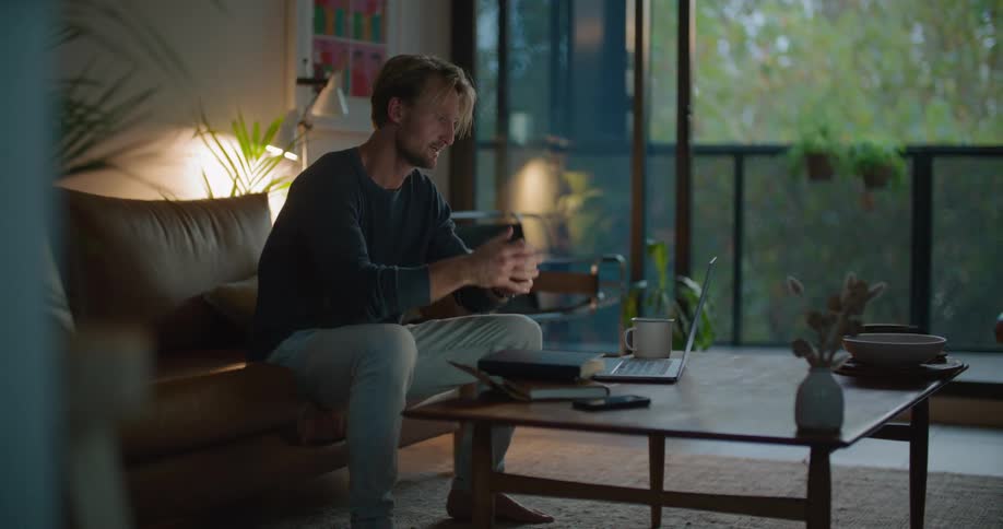 A man talks on his cell phone and sits back in the couch