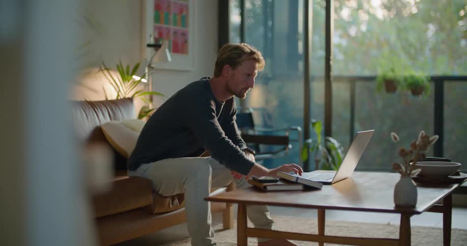 A man is sitting in his living room with his laptop