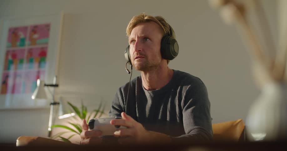 Man talks via gaming headset as he successfully manipulates game controller