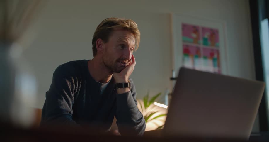 A man is talking on his laptop at home