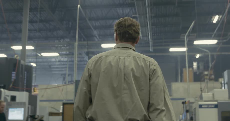 Supervisor walking among the machinery and employees working on a warehouse