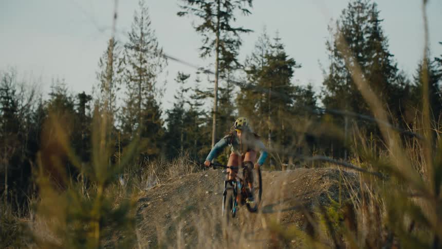 A woman jumps over the hill on a mountain bike