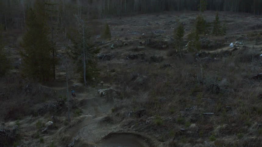 A person on a bicycle is seen from above as they race along a dirt bicycle course