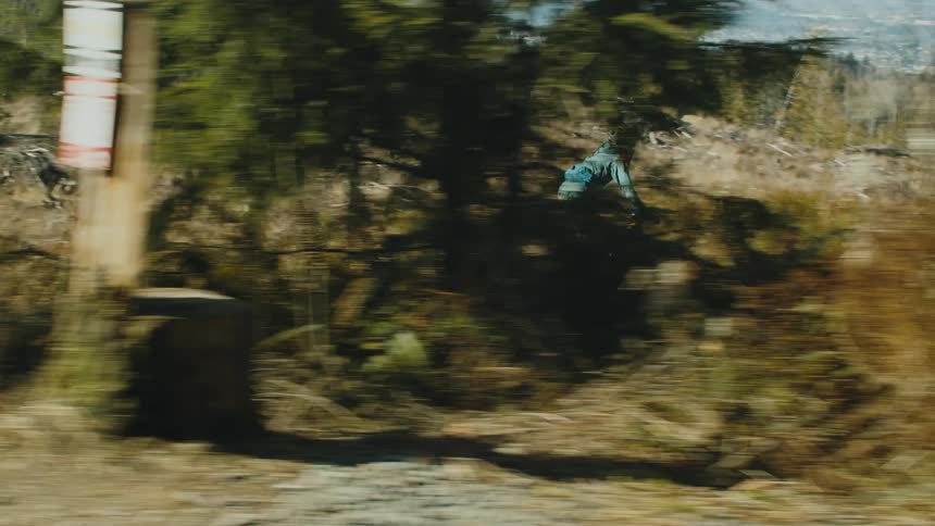 A girl wearing a helmet is riding a bike on a trail near the woods