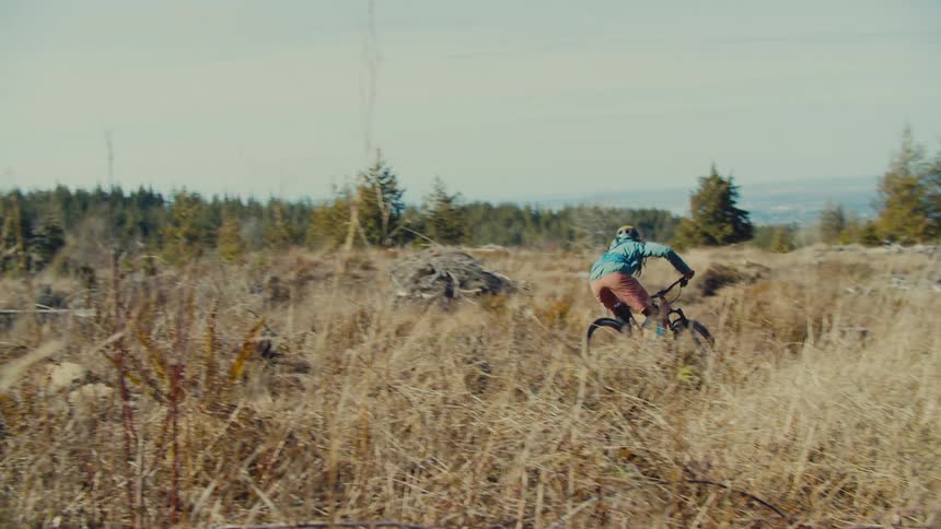 A person on a bicycle leaps as they come off of a small incline along a dirt bicycle course