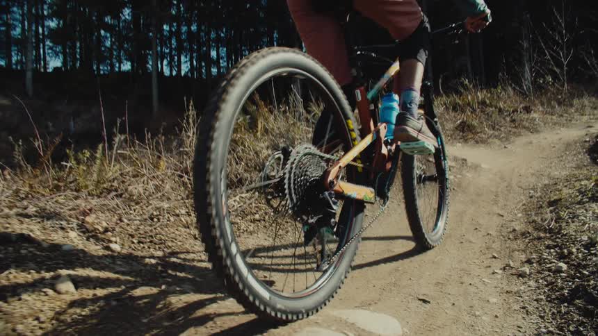 A person pedaling a mountain bike on a trail in the forest at daytime