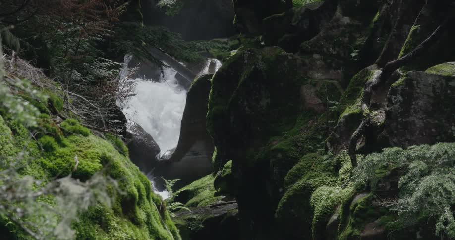 Turbulent river between the rocks covered in green moss on the mountain