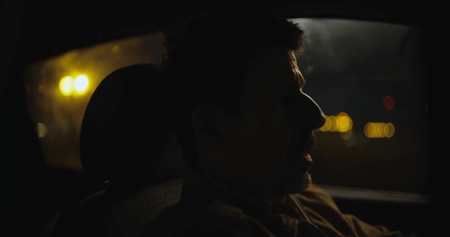A man talks as he drives a car at night