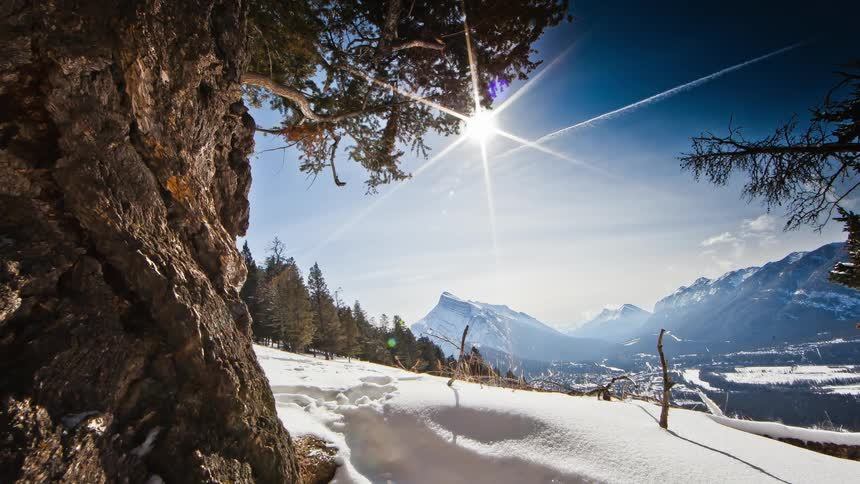 The sun is up high over a mountain range in the distance