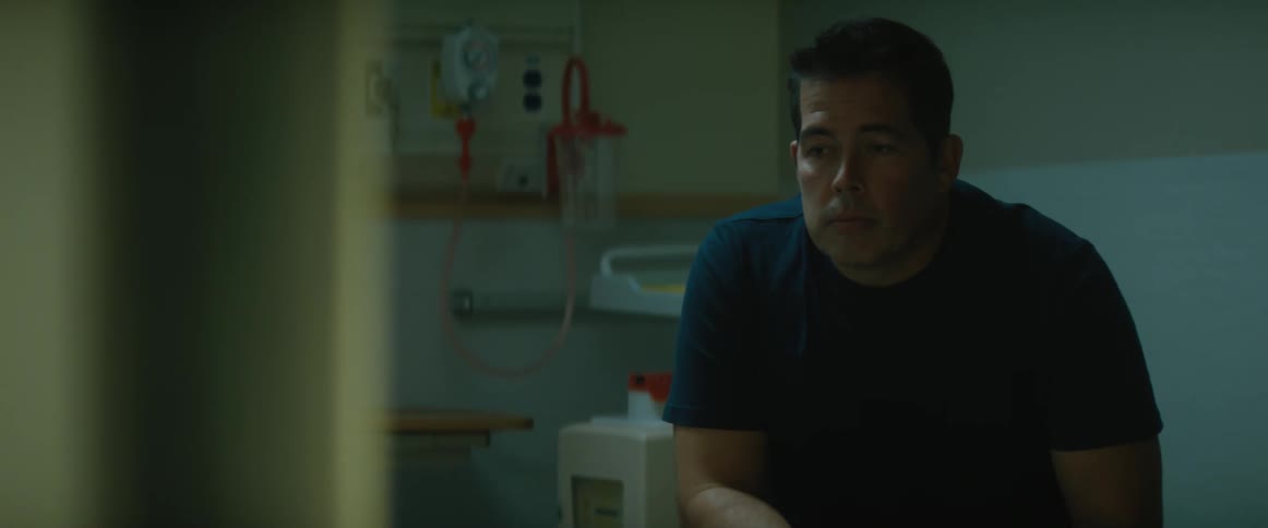 Man sitting on a dimly lit hospital room waiting