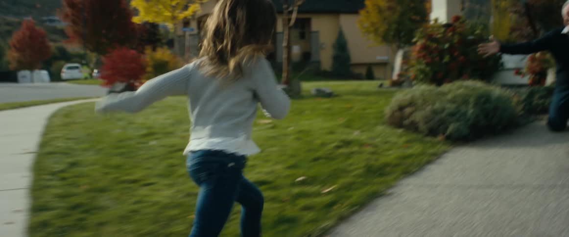 A little girl gets out of the car and runs to hug her grandfather in front of his home