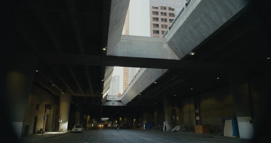 A road is located below an overpass at the base of several tall office buildings