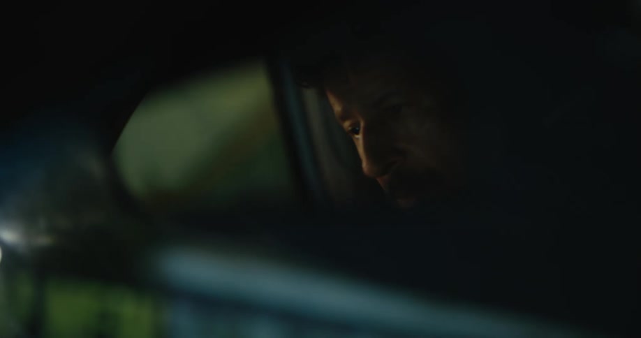 The reflection of a driver and the cars he is passing at night