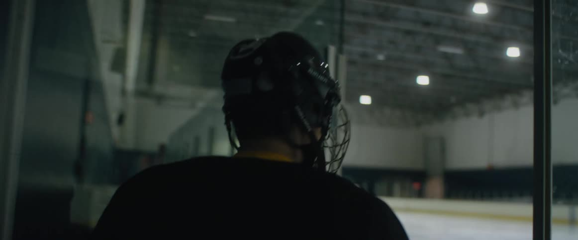 Hockey player wearing protective gear skates onto ice rink