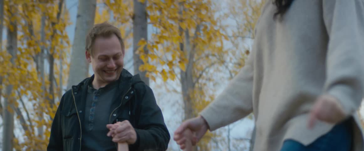 Parents swing their daughter up by her arms while walking through the woods